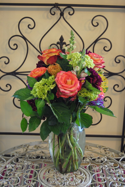 A vibrant arrangement of coral roses and seasonal blooms by Queen Anne’s Flower Shop